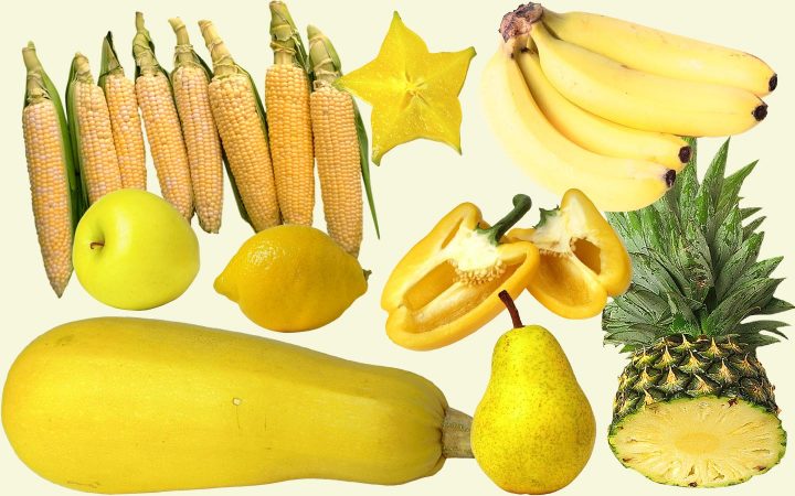 Een assortiment gele vruchten en groenten, waaronder courgette, appel, peer, ananas, paprika, bananen, citroenen, stervrucht en suikermaïs.