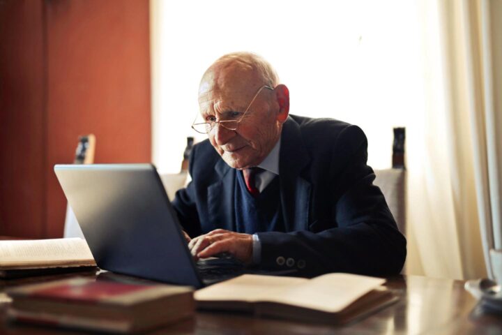 Een slimme bejaarde die aan een computer werkt