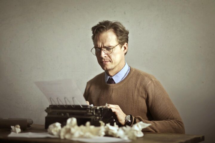 Een man die op een typemachine typt en vanwege perfectionisme zijn schrijfwerk vele malen herhaalt