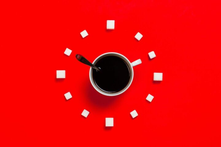 Een klok gesymboliseerd door een koffiekopje en suikerklontjes.