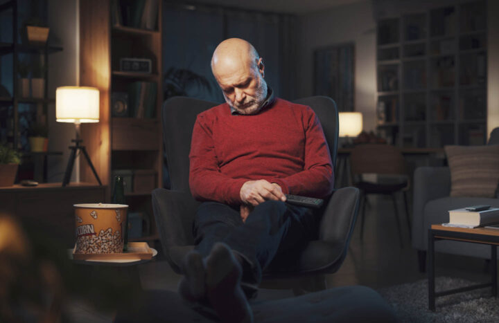 Een senior die voor de tv in slaap valt